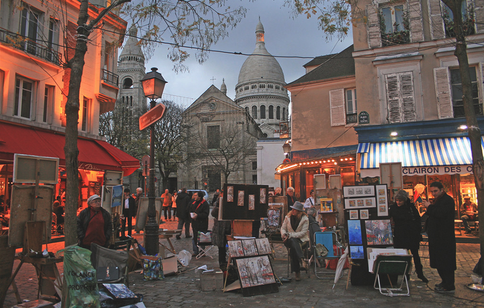 Artists painting and displaying their work in the Place du Tertre, with charming Parisian buildings in the background.